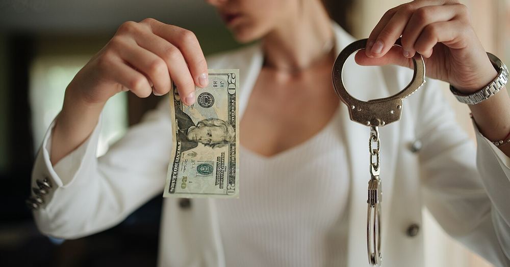 Woman holding cash and handcuffs in a tense moment of confrontation indoors