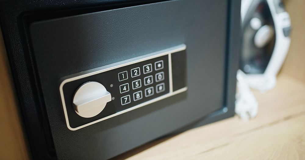 A black security safe with a numeric keypad is set within a wooden cabinet