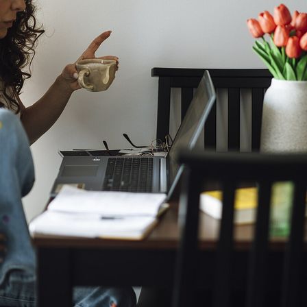 Working on a laptop while enjoying a cup of coffee at home